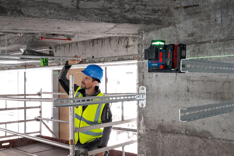 GLL 18V-120-33 CG A person wearing safety equipment aligns metal bars using a laser leveling tool.