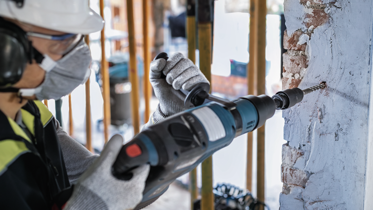 PRO Hammer Adapter, SDS max to SDS plus A person wearing safety equipment drills into a concrete wall.