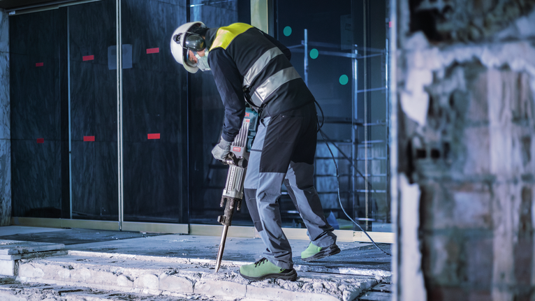 PRO HEX-5C Pointed Chisel 30 mm, 30 x 400 mm Person wearing safety equipment breaking concrete with a demolition hammer.