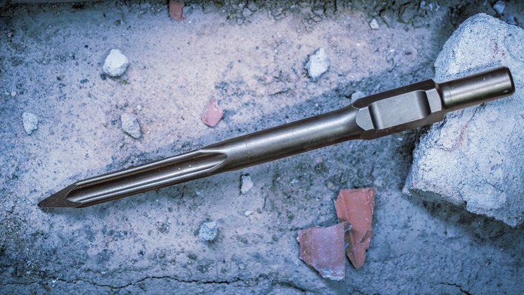PRO HEX-5C Pointed Chisel 30 mm, 30 x 400 mm Pointed chisel lying on a concrete surface with debris and a concrete block.