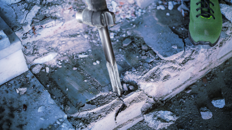 PRO HEX-5C Pointed Chisel 30 mm, 30 x 400 mm Person uses a heavy-duty tool to break concrete steps.