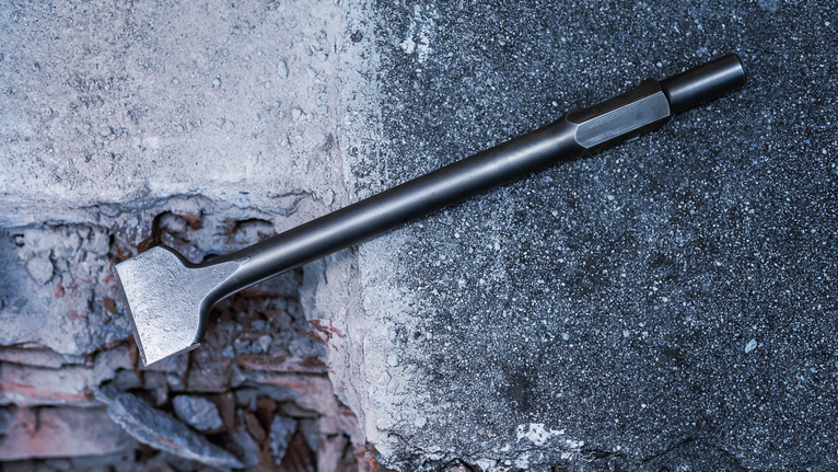 Flat chisel resting on a rough concrete surface.