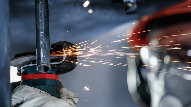 PRO Stainless Steel and Metal Bonded Cutting Disc, 76 x 1 x 10 mm Worker wearing safety equipment grinds metal pipe, creating sparks.