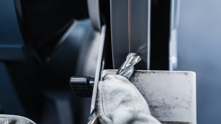 PRO Metal Grinding Wheel, 200 x 25 x 32 mm, G60 Person wearing safety equipment sharpens a drill bit on a grinding machine.