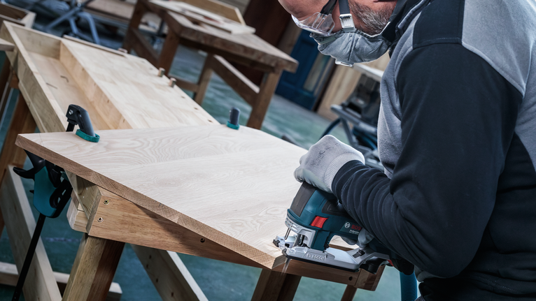 PRO Hardwood clean T101BF Jigsaw Blade, 100 mm, 5 pcs Person wearing safety equipment uses a jigsaw to cut a wooden board.