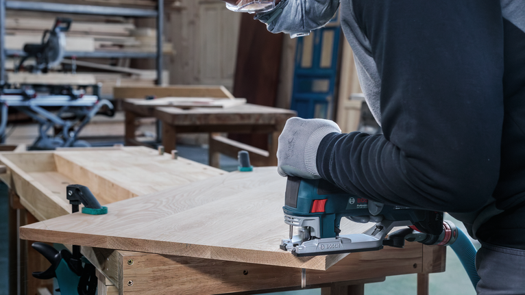 PRO Hardwood clean T101BF Jigsaw Blade, 100 mm, 5 pcs A person wearing safety equipment cuts wood with a jigsaw in a workshop.