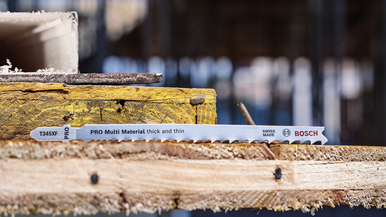 PRO Multi Material thick and thin T345XF Jigsaw Blade, 132 mm, 3 pcs Jigsaw blade rests on stacked wooden planks at a construction site.