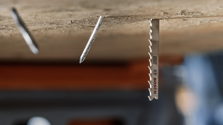 PRO Multi Material thick and thin T345XF Jigsaw Blade, 132 mm, 3 pcs A metal saw blade installed in wood next to two protruding nails.