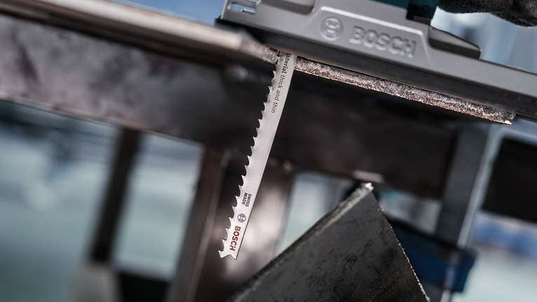 PRO Multi Material thick and thin T345XF Jigsaw Blade, 132 mm, 3 pcs Person wearing safety equipment uses a jigsaw to cut through a metal sheet.