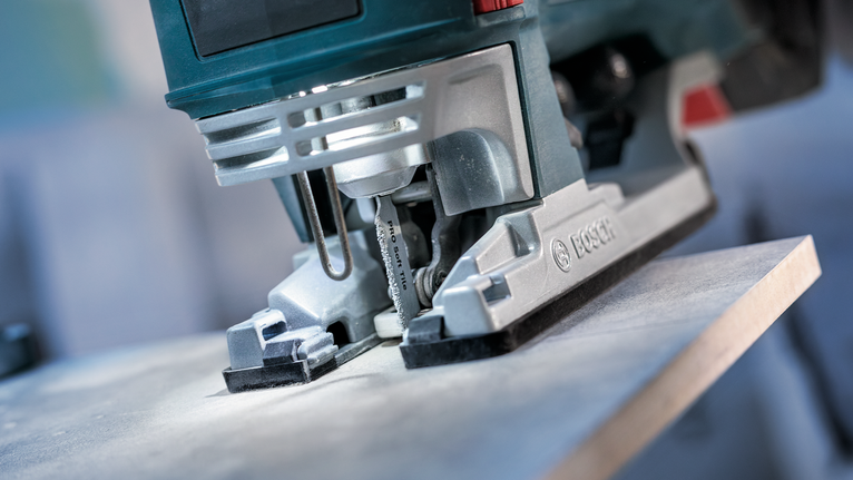 PRO Soft Tile T130RF Jigsaw Blade, 83 mm, 3 pcs Jigsaw cutting through a wooden board in a close-up workshop setting.