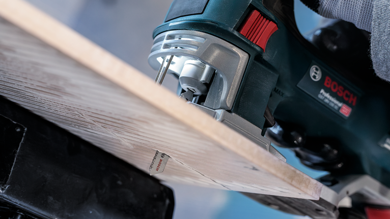 PRO Soft Tile T130RF Jigsaw Blade, 83 mm, 3 pcs Person guides a jigsaw to cut through a wooden board.