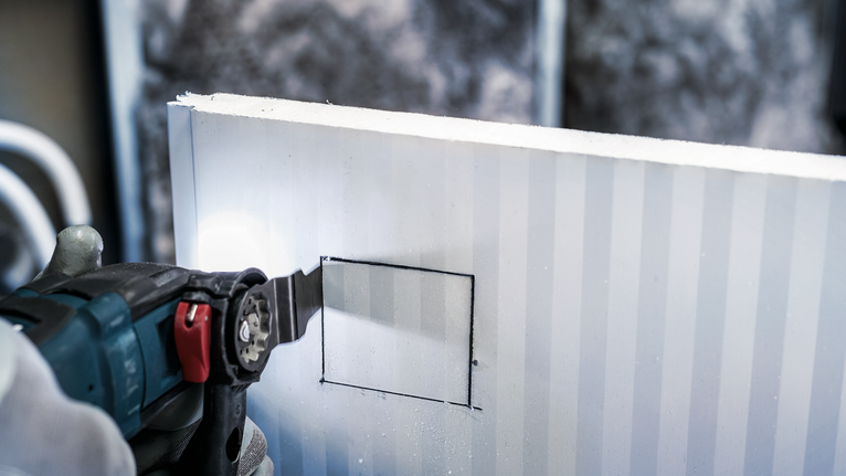 PRO AIZ 32 APIB Plunge Cut Blade, 32 x 50 mm Person wearing safety equipment cutting a square opening in drywall with a power tool.