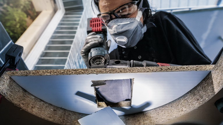 PRO AIZ 32 APIB Plunge Cut Blade, 32 x 50 mm Person wearing safety equipment drills a hole in a wooden board.