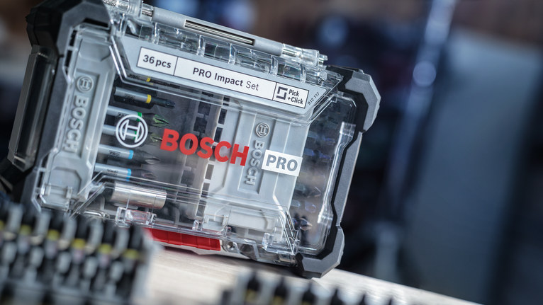 Clear plastic case containing assorted screwdriver bits on a wooden surface.