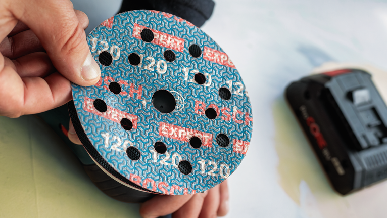 Person attaches sanding disc to a power sander.