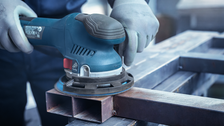 Object #200471073: 7390919_app_web_4 Worker wearing safety equipment sands a metal beam using an electric sander.