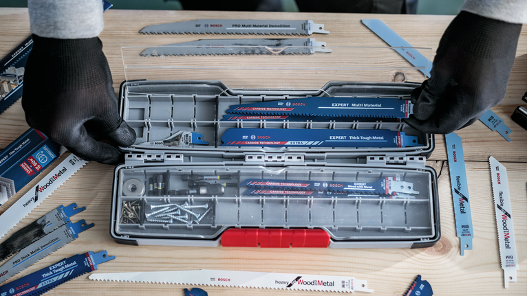 PRO Tough Box Large for Accessories, 50 x 120 x 355 mm Person wearing safety equipment organizes assorted saw blades and screws in a tool case.