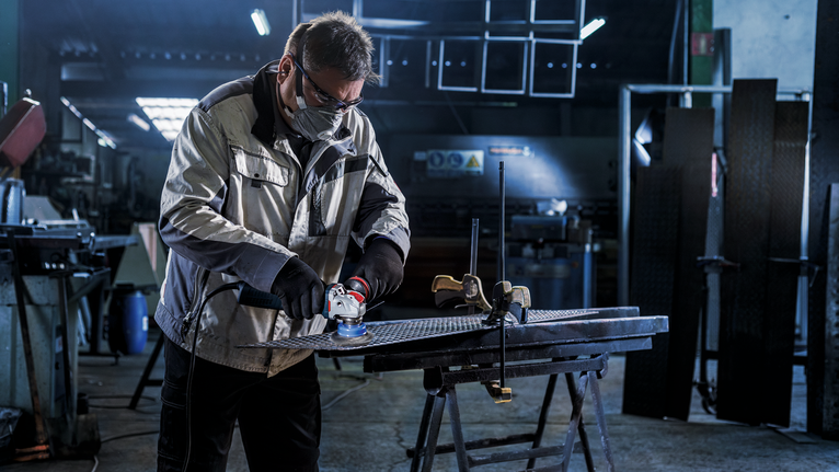 PRO Stainless Steel clean X-Lock Cup Brush, 75 x 0.3 mm Person wearing safety equipment grinds metal on a workbench in a workshop.