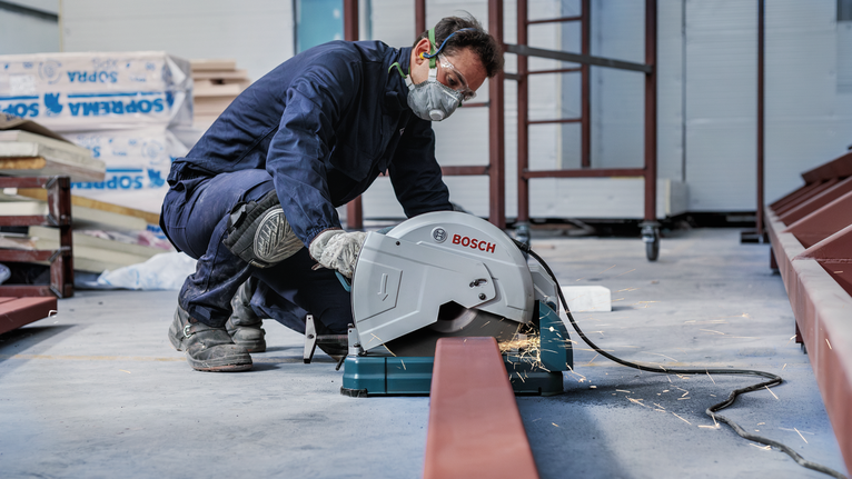 PRO Metal Cutting Disc, 305 x 3 x 25.4 mm A person wearing safety equipment cuts a metal beam with a power saw, sparks flying.