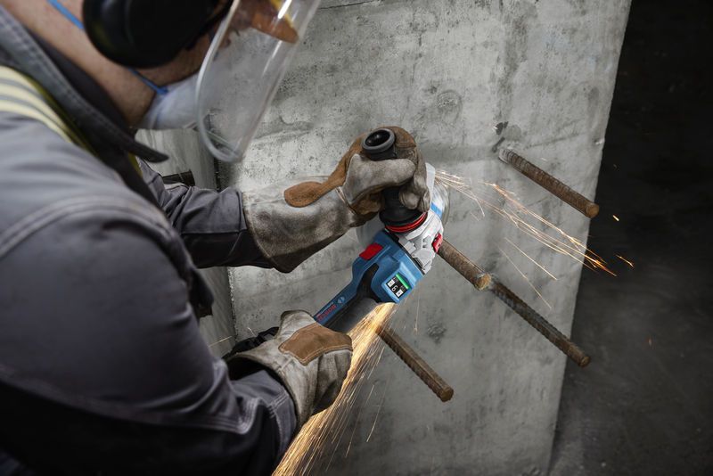 GWS 18V-15 S A person wearing safety equipment grinds exposed rebar on a concrete wall.
