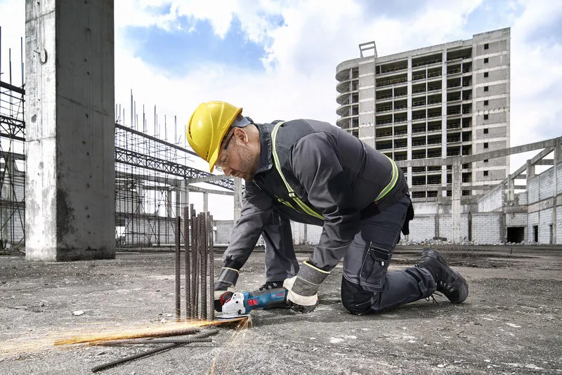 GWS 18V-11 S A person wearing safety equipment cuts rebar with a power tool at a construction site.