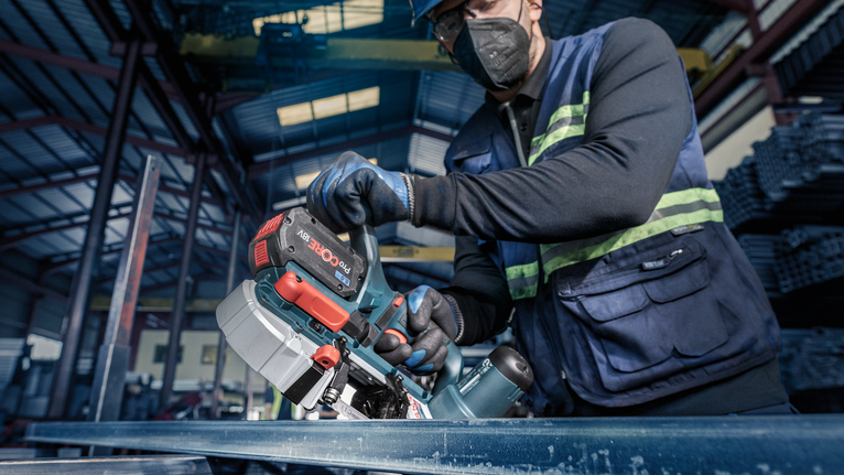 PRO CB281418 Band Saw Blade, 733 mm, 2 pcs A person wearing safety equipment uses a cordless bandsaw to cut a metal beam.
