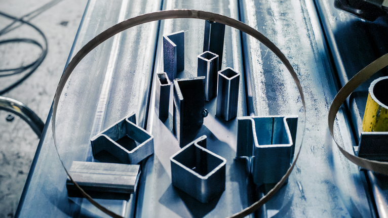 PRO CB281418 Band Saw Blade, 733 mm, 2 pcs Metal pipes and profiles are arranged inside a bandsaw blade on a workshop table.