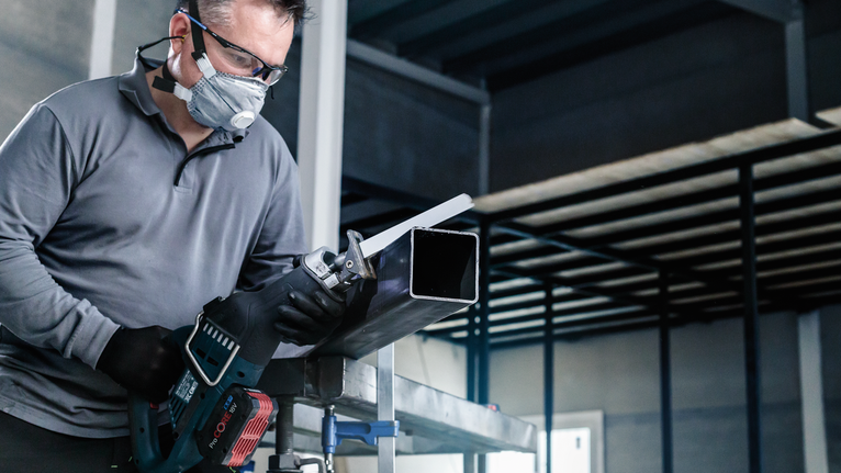 PRO Thick Metal precise S1137HBF Blade, 1.1 x 25 x 225 mm, 5 pcs A person wearing safety equipment uses a reciprocating saw to cut a metal pipe.
