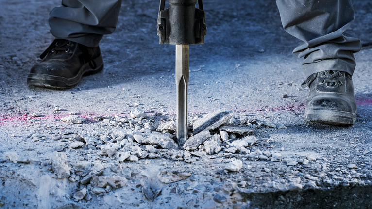 PRO HEX-4C Flat Chisel 28 mm, 35 x 400 mm Person wearing safety equipment breaks concrete with a demolition hammer.