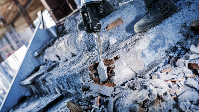 PRO HEX-4C Flat Chisel 28 mm, 35 x 400 mm Person wearing safety equipment demolishes concrete steps with a power chisel.