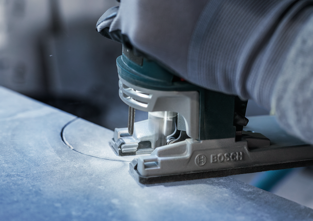 PRO Soft Tile T130RF Jigsaw Blade, 83 mm, 3 pcs Person wearing safety equipment guides a jigsaw cutting a curved line in stone.