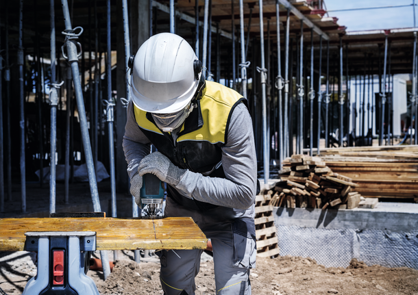 PRO Multi Material thick and thin T345XF Jigsaw Blade, 132 mm, 3 pcs A person wearing safety equipment cuts a wooden plank with a power tool at a construction site.
