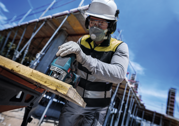 PRO Multi Material thick and thin T345XF Jigsaw Blade, 132 mm, 3 pcs Person wearing safety equipment cuts wood with a jigsaw at a construction site.