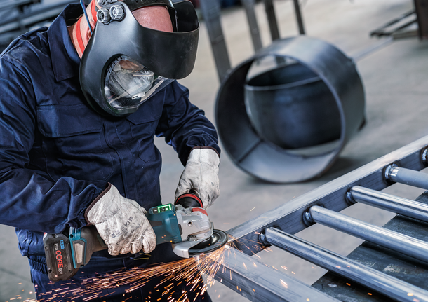 PRO Backing Pad Hard, 125 mm, X-Lock Person wearing safety equipment grinds metal beams, creating sparks.