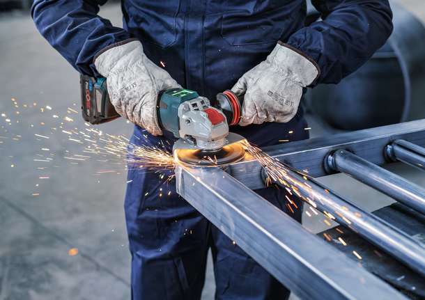 PRO Backing Pad Hard, 125 mm, X-Lock A person wearing safety equipment grinds metal, creating sparks.