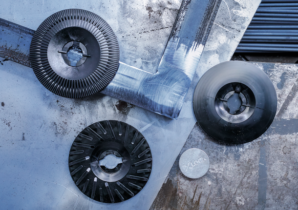 PRO Backing Pad Hard, 125 mm, X-Lock Three grinding discs and a metal adapter lay on a scratched metal surface.