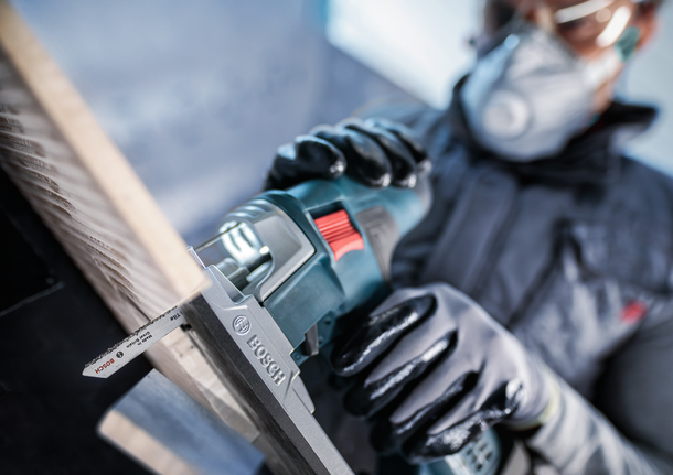 PRO Soft Tile T130RF Jigsaw Blade, 83 mm, 3 pcs Person wearing safety equipment uses a reciprocating saw to cut wood.