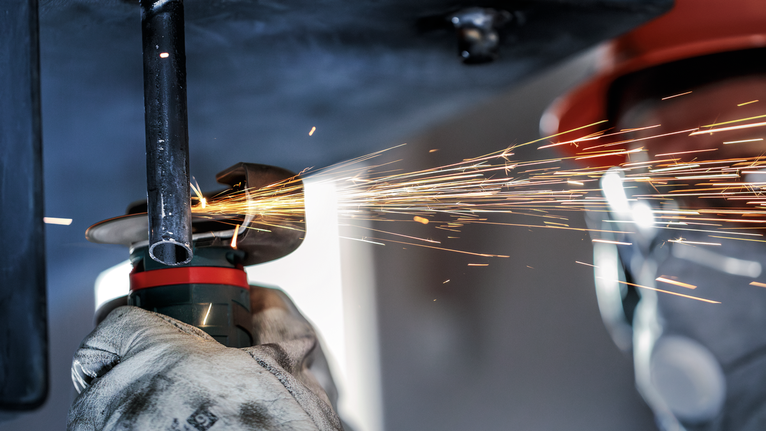 PRO Stainless Steel and Metal Bonded Cutting Disc, 76 x 1 x 10 mm Person wearing safety equipment grinds metal pipe as sparks fly.
