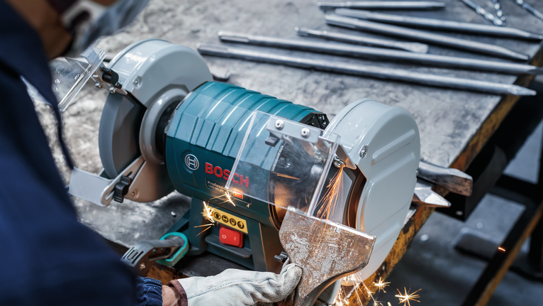 PRO Metal Grinding Wheel, 200 x 25 x 32 mm, G60 A worker wearing safety equipment grinds a metal piece with a bench grinder.