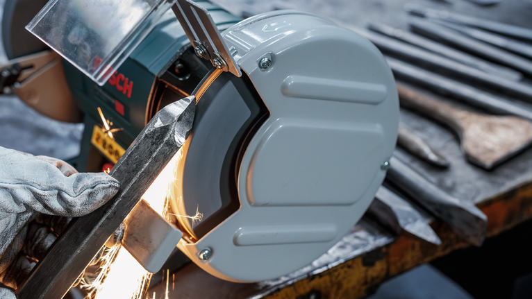 PRO Metal Grinding Wheel, 200 x 25 x 32 mm, G60 Person wearing safety equipment grinds metal on a bench grinder with sparks flying.