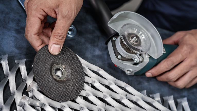 PRO Semi-Flexible Grinding Disc, 100 x 2 x 16 mm Worker changing a grinding disc on a power tool near a metal grate.