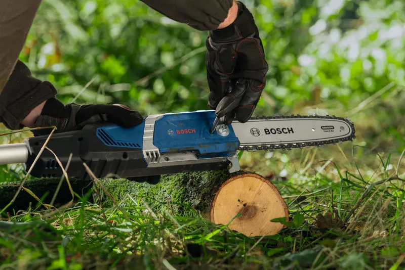 A person wearing safety equipment adjusts a cordless telescopic pruner cutting a tree branch.