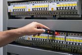 Person testing electrical panel with a non-contact voltage tester.