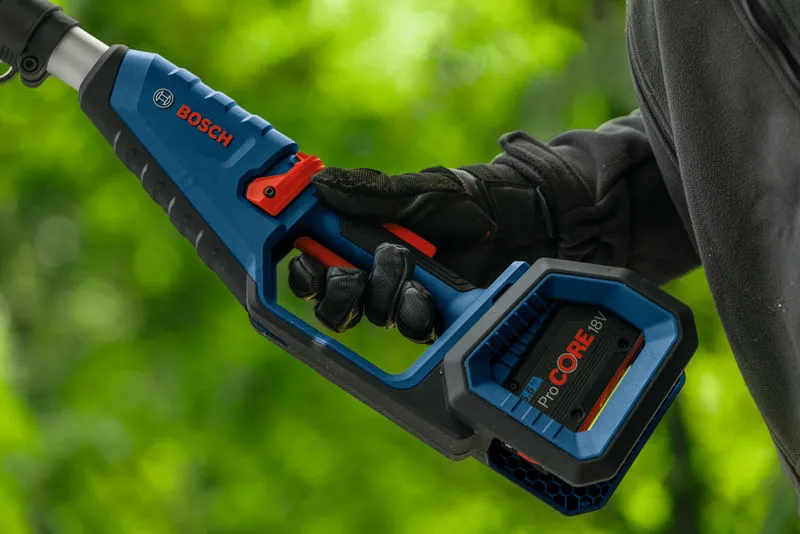 A person wearing safety equipment holds a cordless telescopic pruner outdoors.