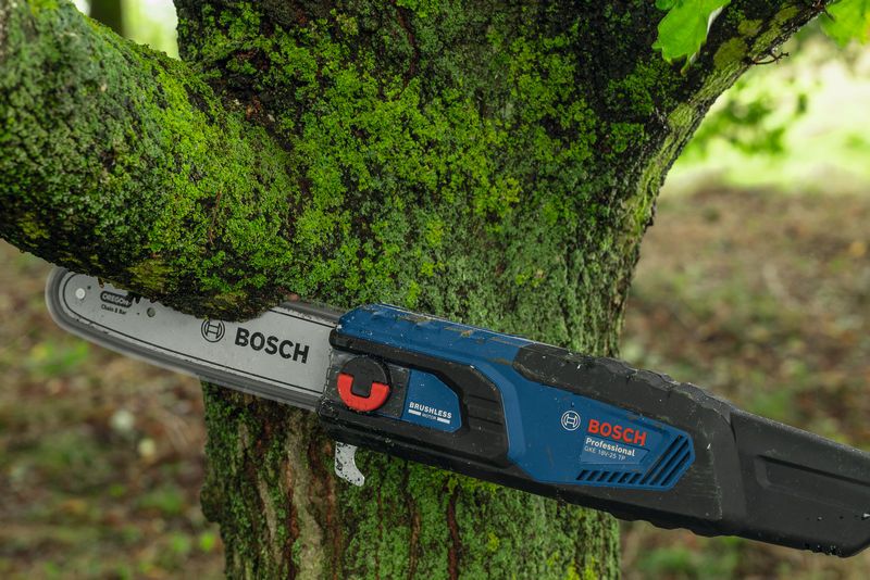 GKE 18V-25 TP Electric chainsaw cutting through a mossy tree branch outdoors.
