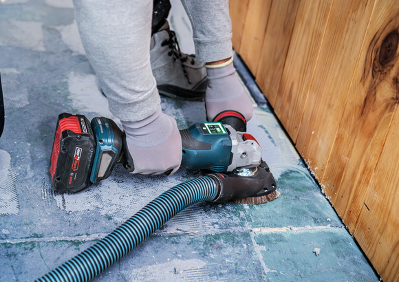 Object #200557588: 7425288_APP_WIDE_1 A person wearing safety equipment sands a concrete floor near a wooden wall.