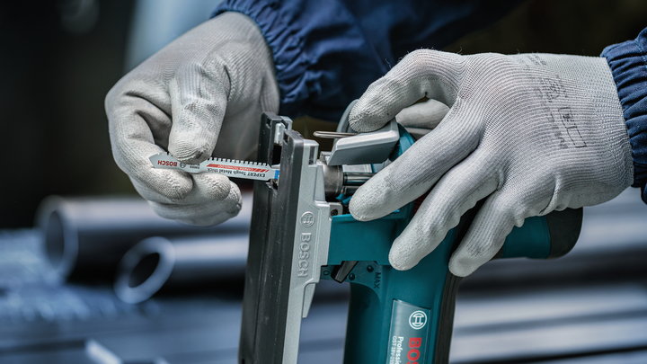 Object #200559113: 7478951_app_web_3 Worker wearing safety equipment inserts a saw blade into a power tool.