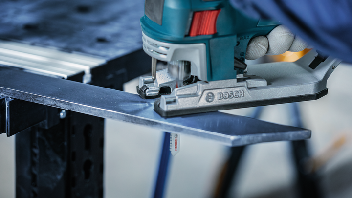 Object #200559119: 7478951_app_web_9 A worker wearing safety equipment uses a jigsaw to cut a metal sheet.