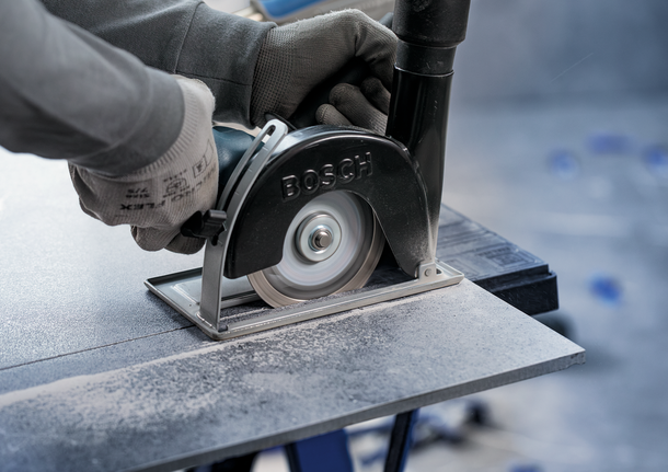 Person wearing safety equipment uses a circular saw to cut a tile.