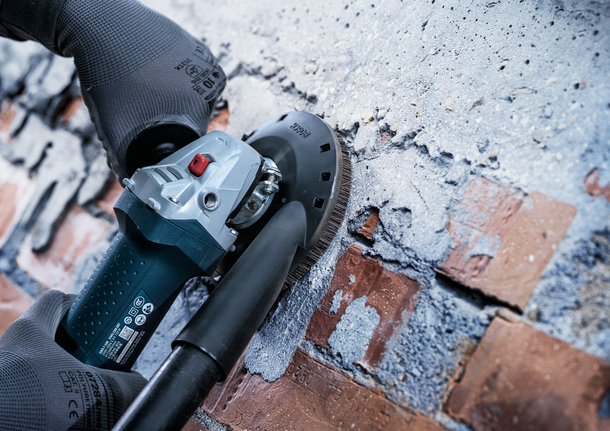 Bosch angle grinder with dust extraction on brick wall.